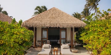 a small hut with lounge chairs and a thatched roof