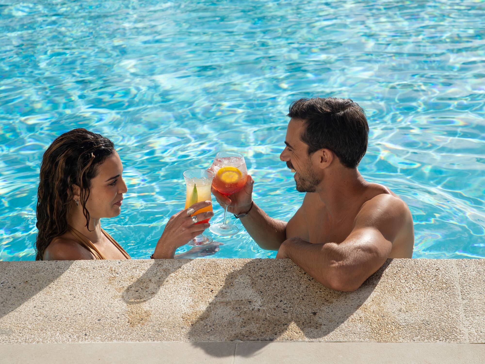 a man and woman in a pool with drinks