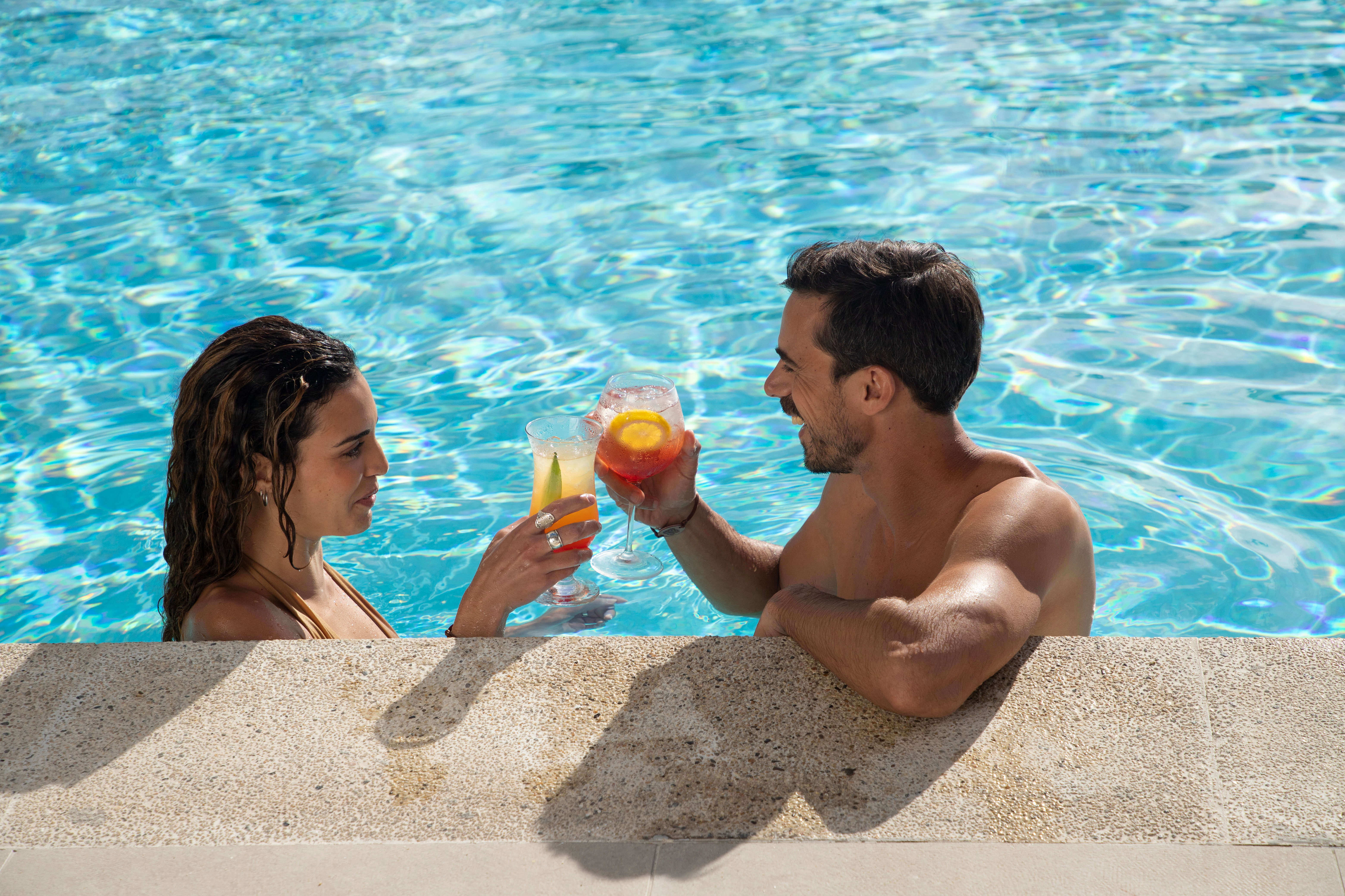 a man and woman in a pool with drinks