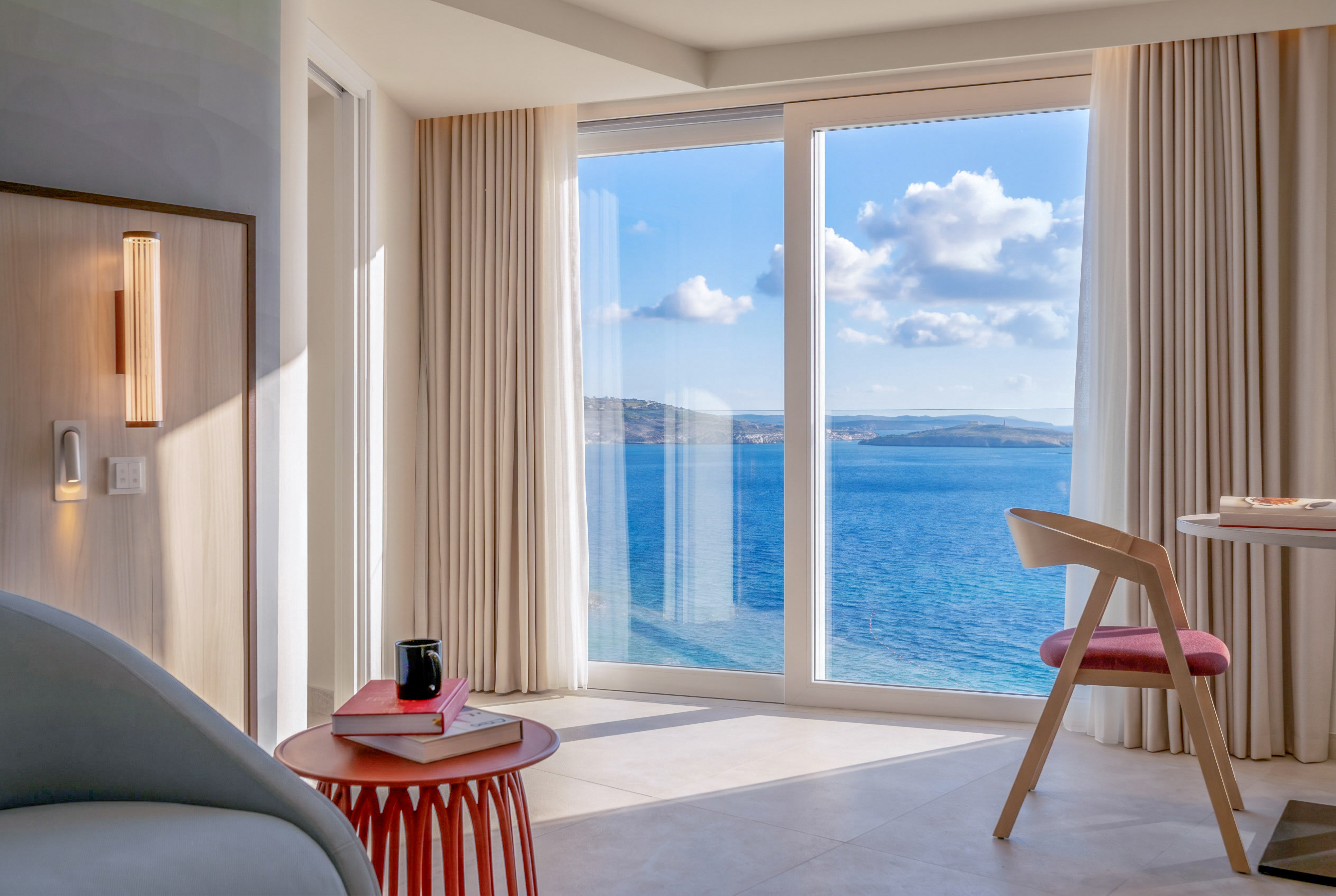 Bright modern hotel room with panoramic sea view from large window.