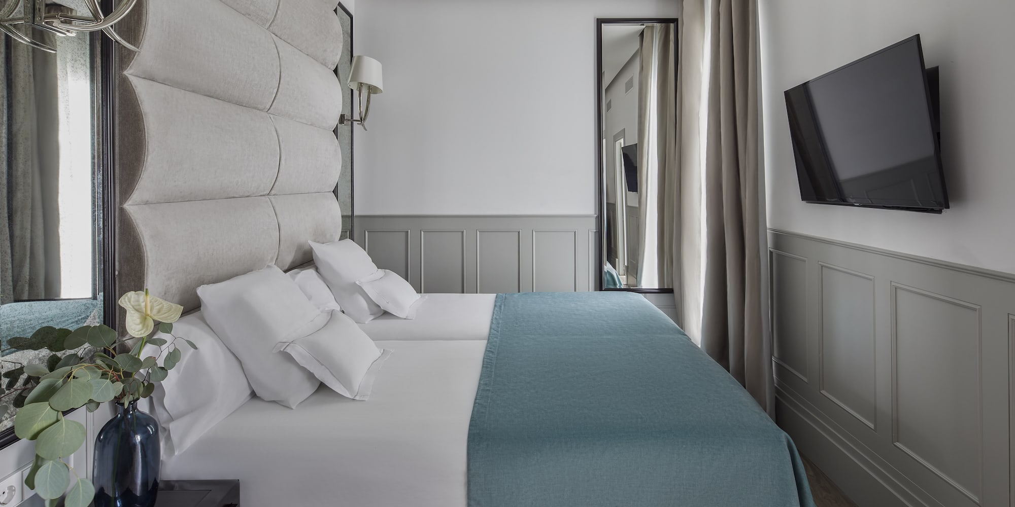 a bed with white sheets and blue blanket in a room