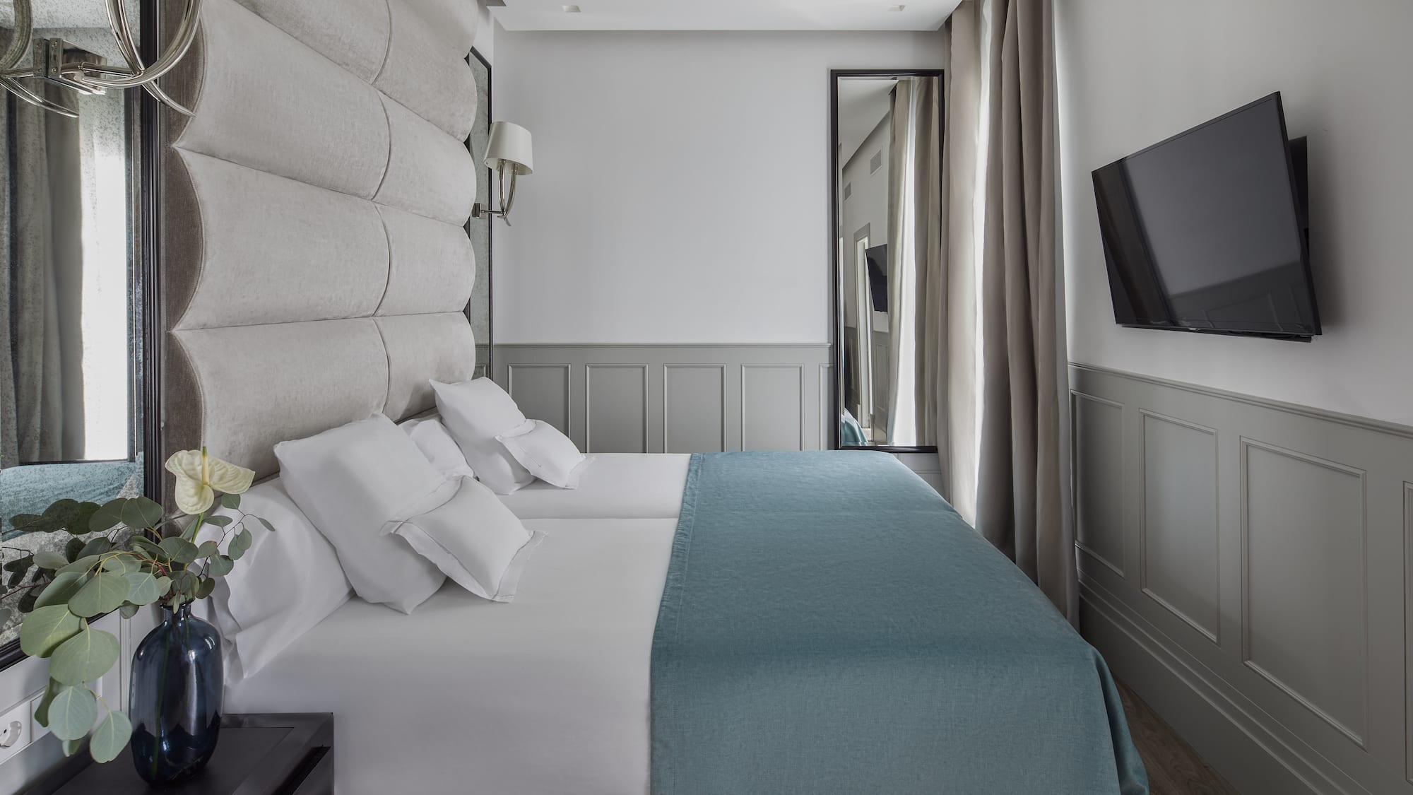 a bed with white sheets and blue blanket in a room