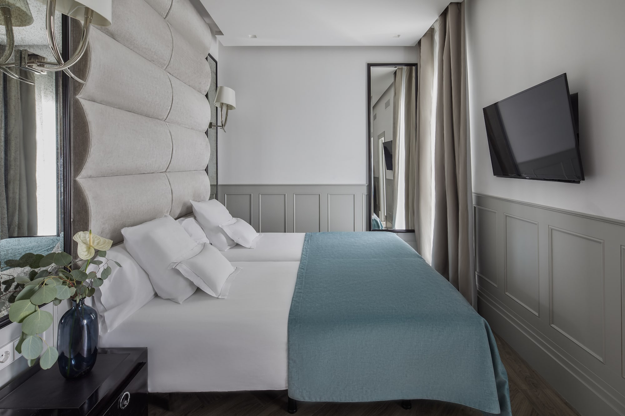 a bed with white sheets and blue blanket in a room