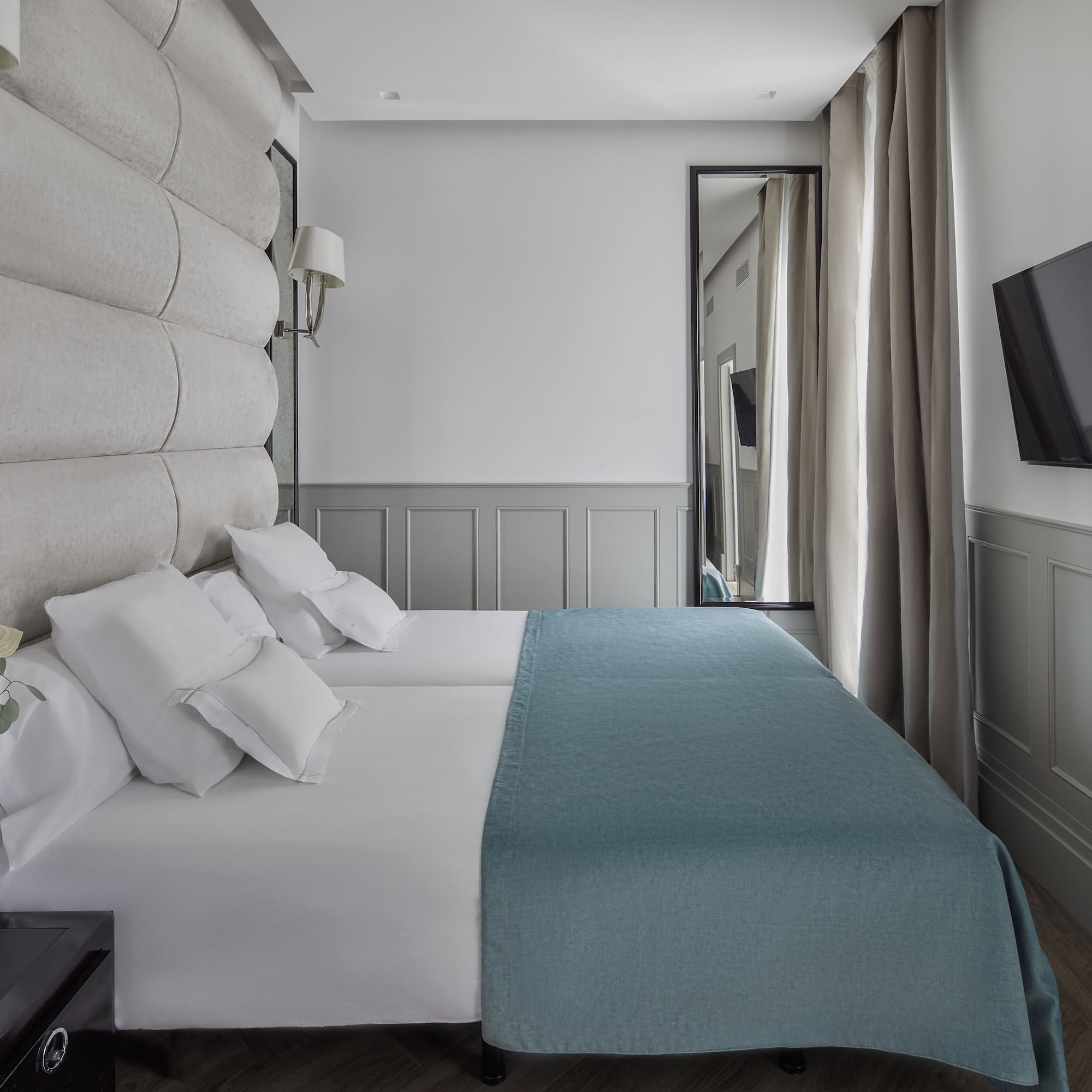 a bed with white sheets and blue blanket in a room