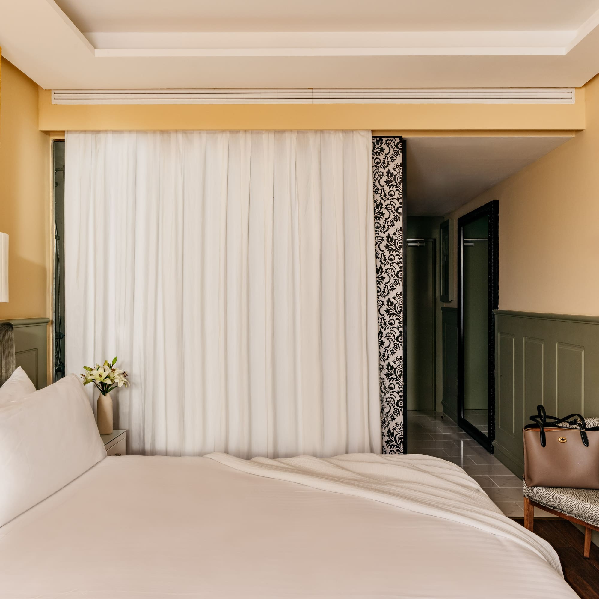 Habitación de hotel con cama, decoración moderna, pared dorada y verde.