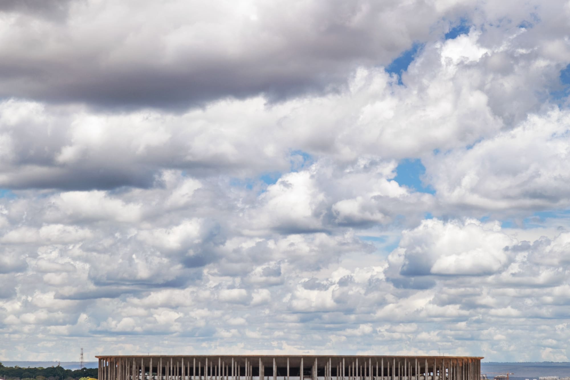 a large round building with trees and a cloudy sky