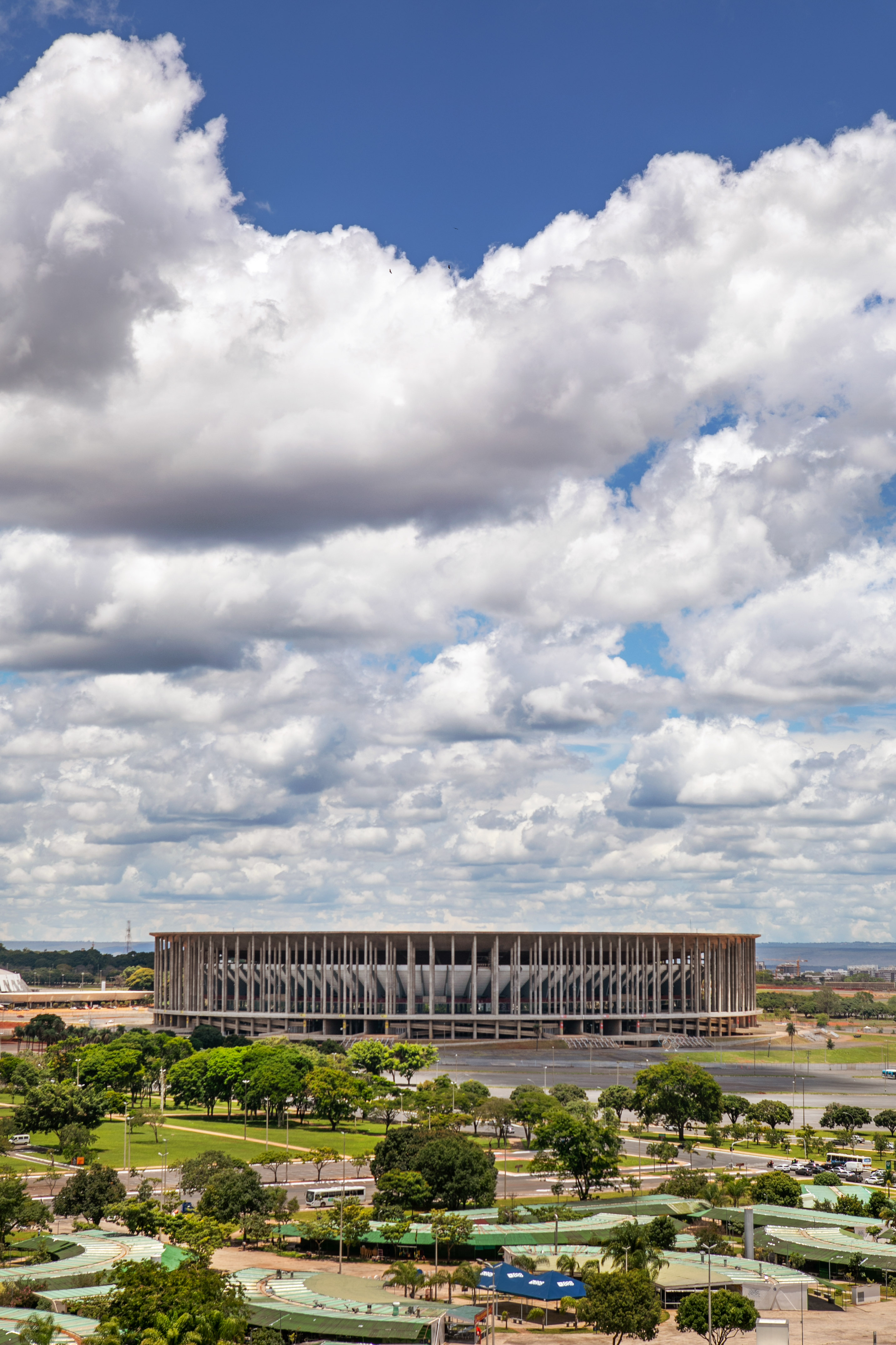 a large round building with trees and a cloudy sky