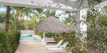 a pool with lounge chairs and a thatched roof