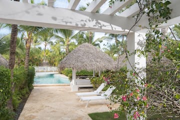 a pool with lounge chairs and a thatched roof