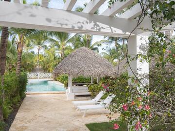 a pool with lounge chairs and a thatched roof