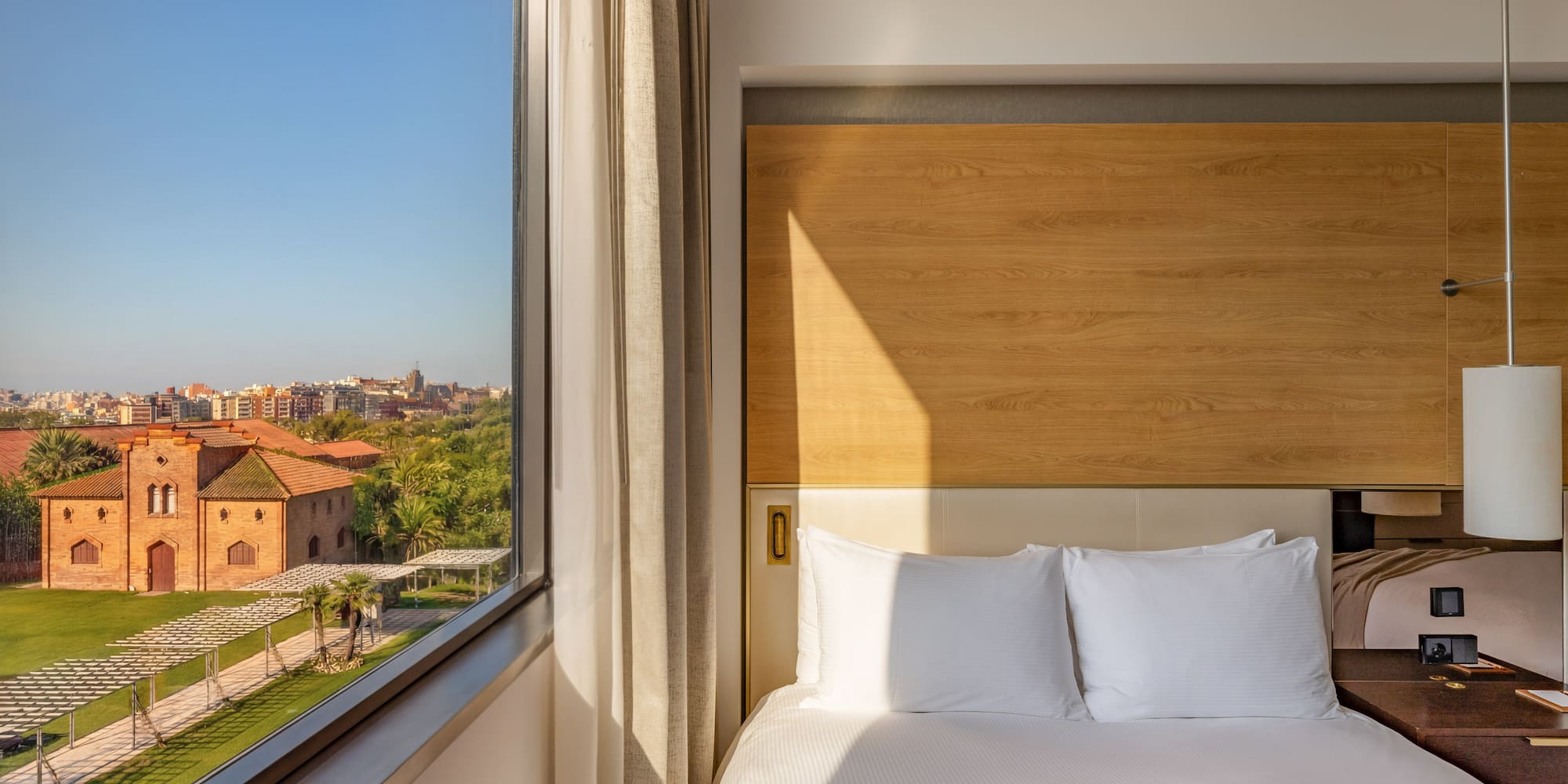 Modern hotel room with comfortable bed and scenic city garden view.