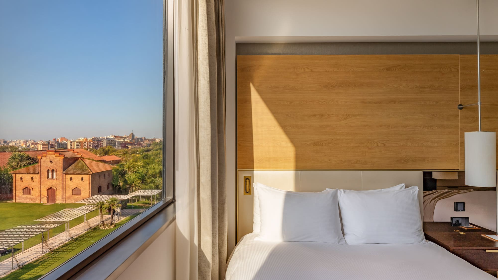 Modern hotel room with comfortable bed and scenic city garden view.