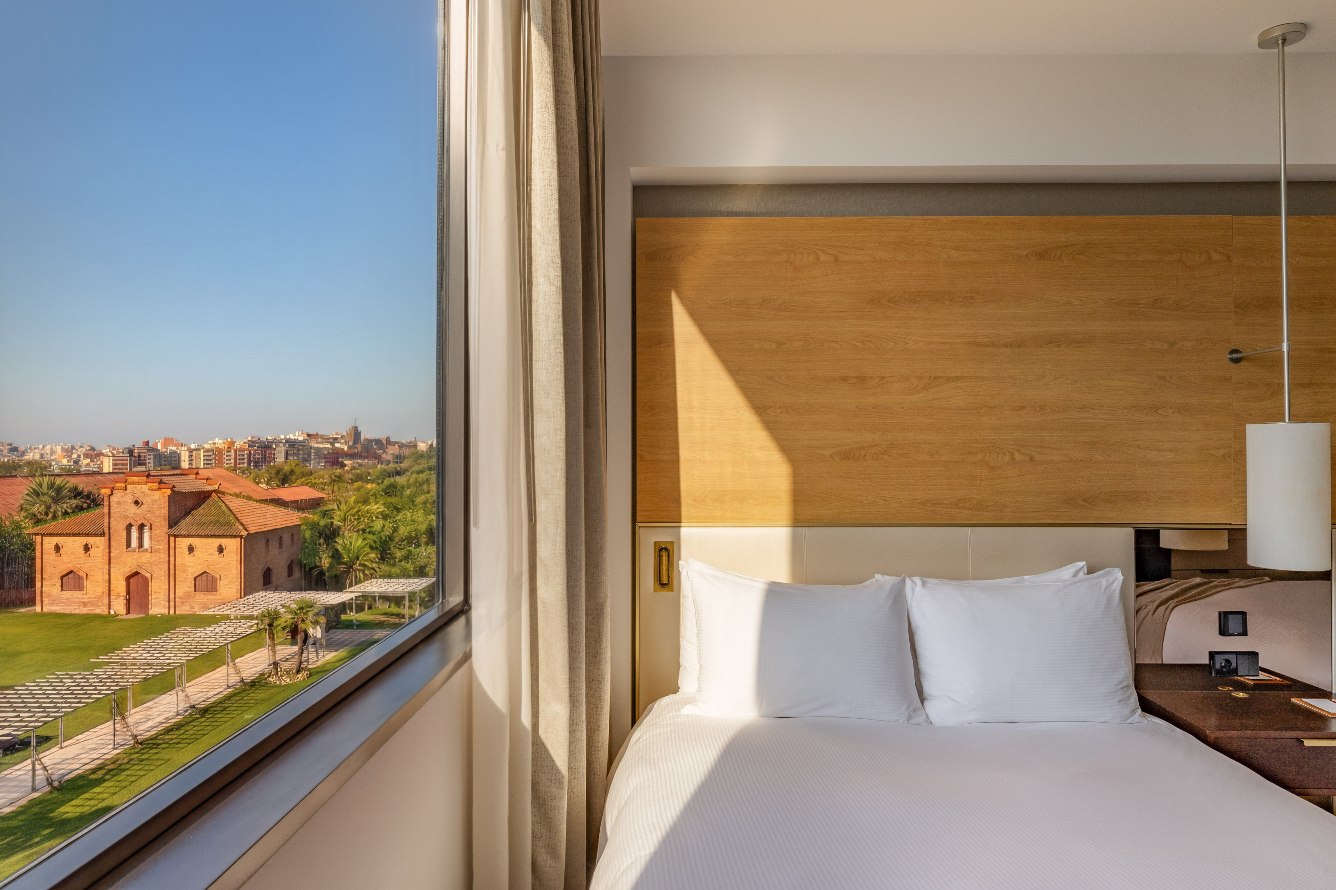 Modern hotel room with comfortable bed and scenic city garden view.