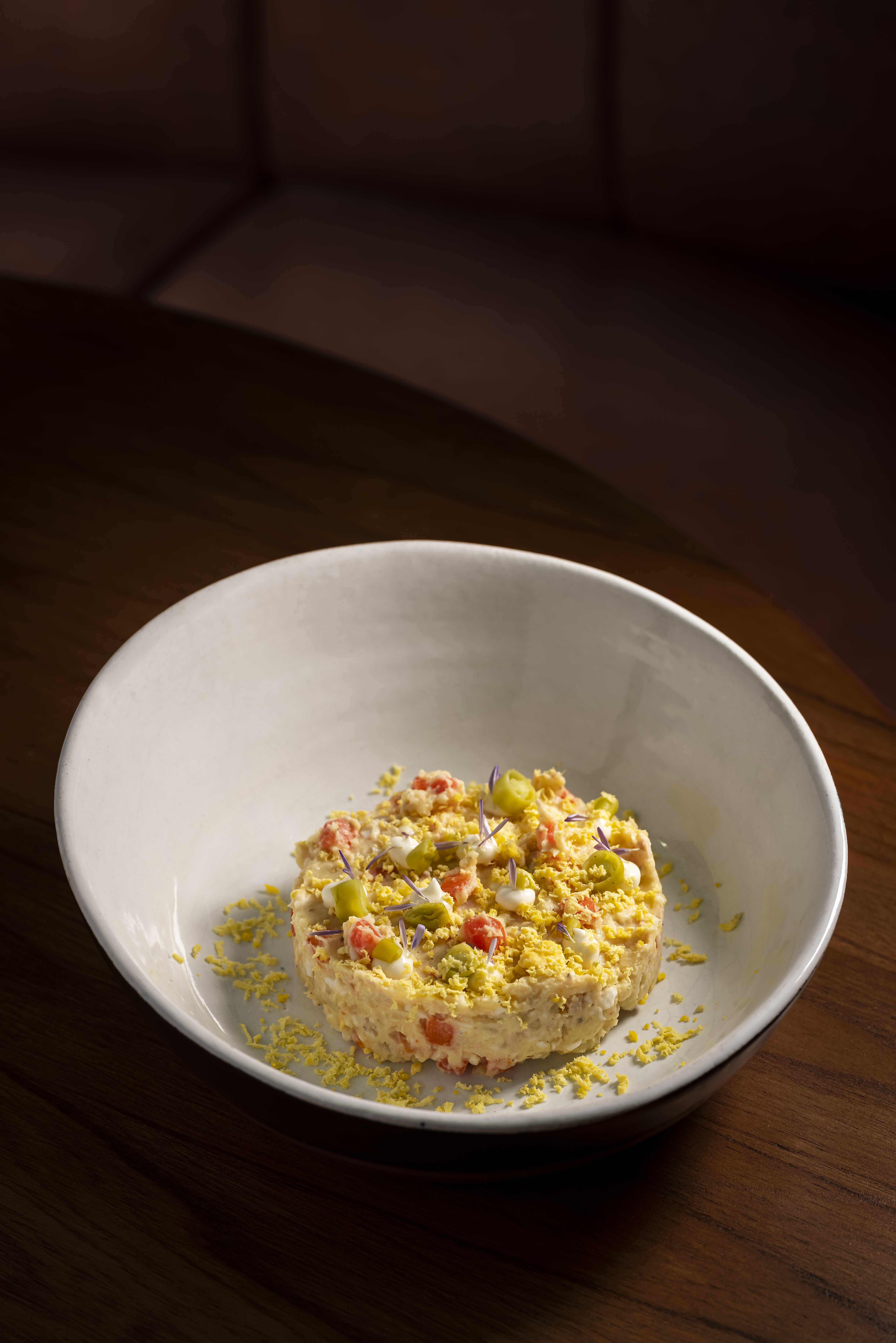 Spanish potato salad (Ensaladilla Rusa) with egg, pickles, and edible flowers.