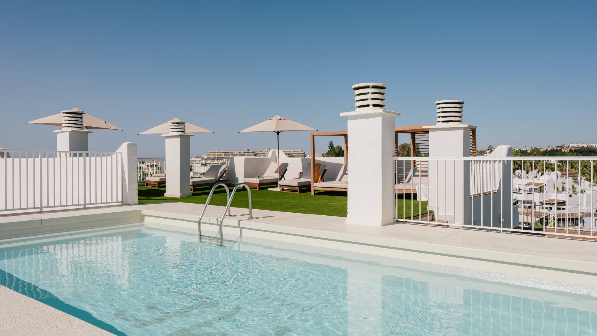 a pool with a white fence and umbrellas
