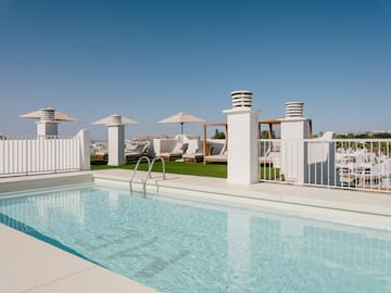 a pool with a white fence and umbrellas