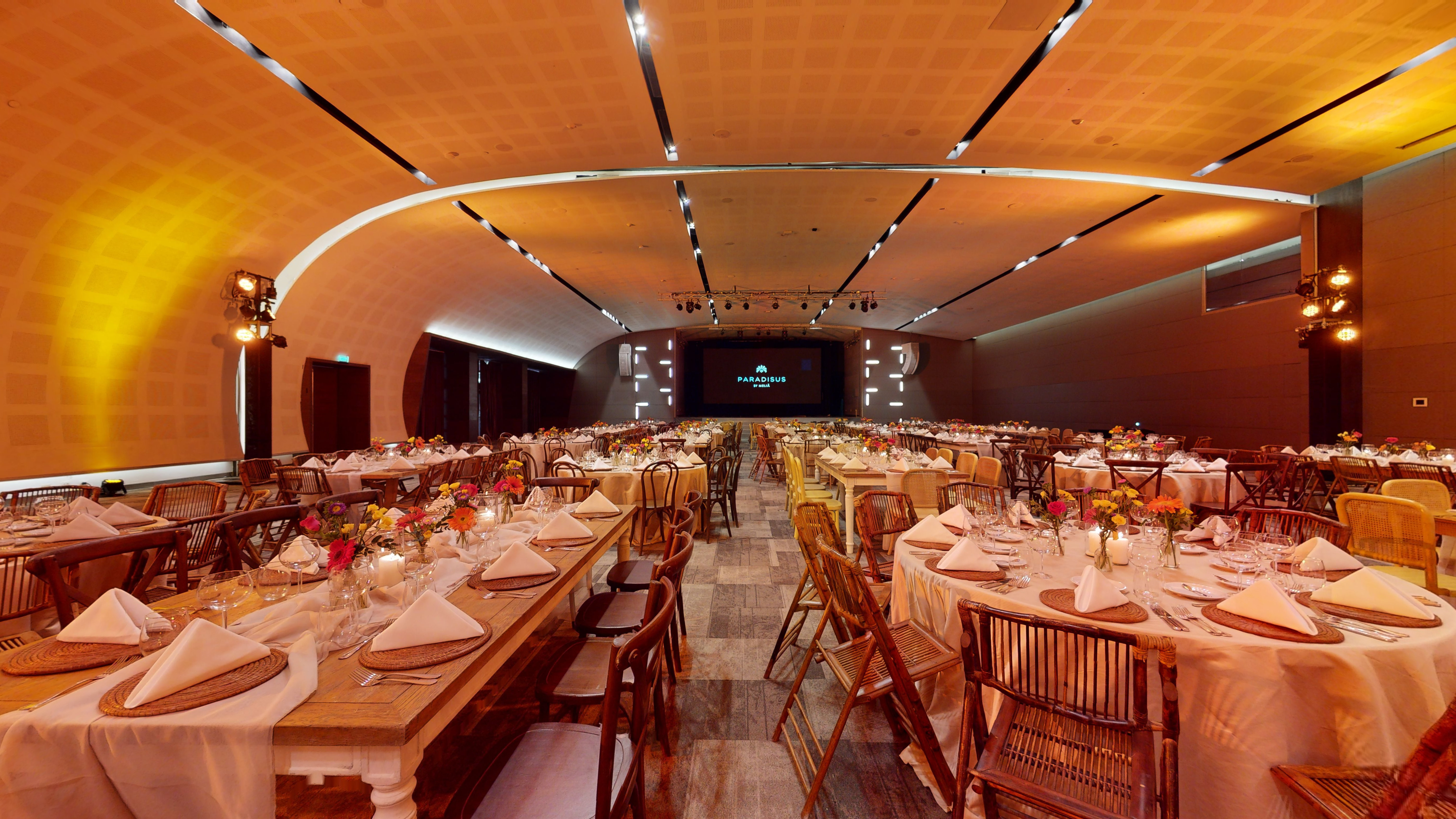 Paradisus resort ballroom with banquet tables, floral decor, and stage.
