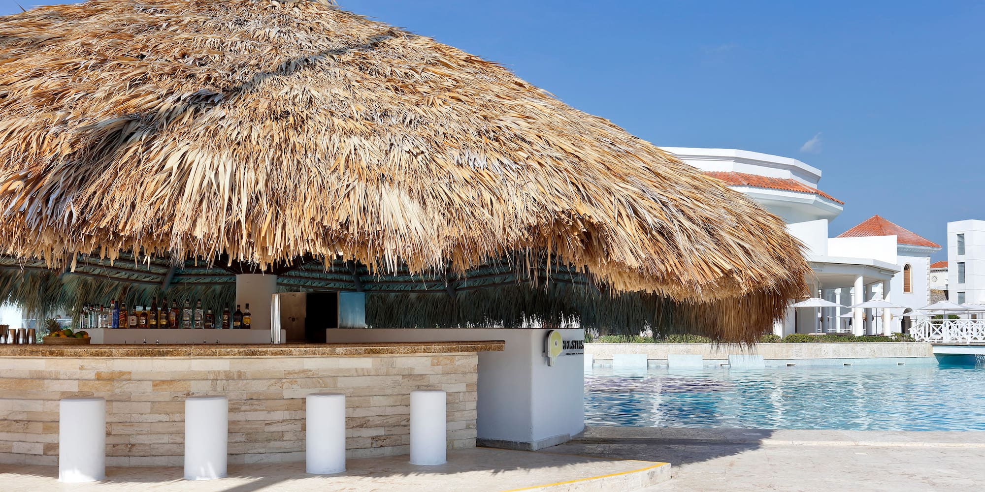 a bar with a straw roof and a pool