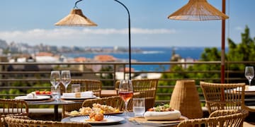 a table with food on it and umbrellas on a balcony