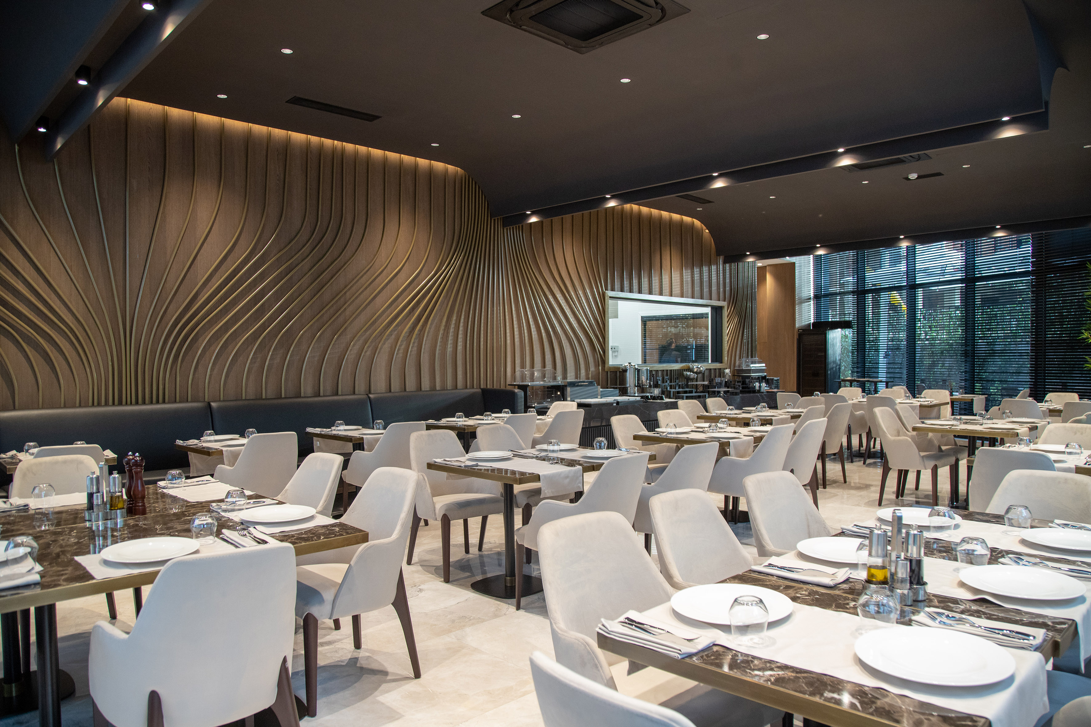 Modern restaurant interior with elegant set tables and a wavy accent wall design.