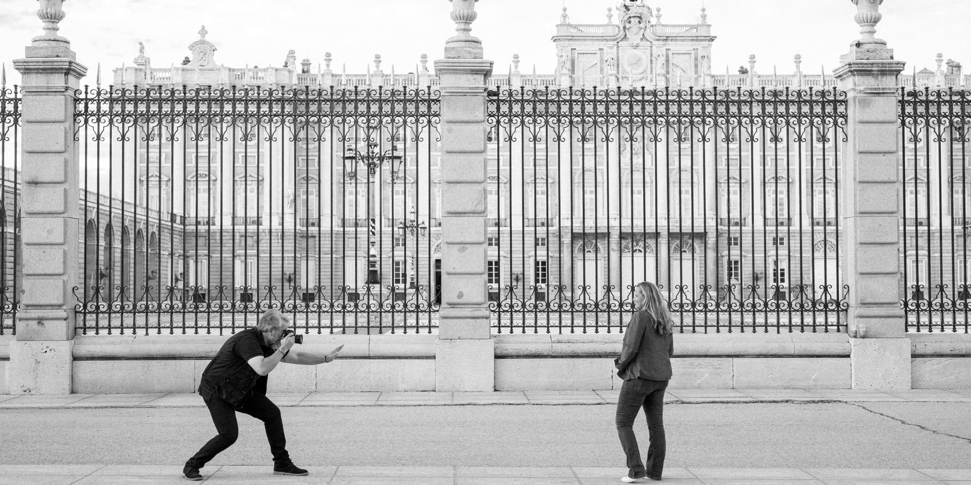 a man and woman standing in front of a fence