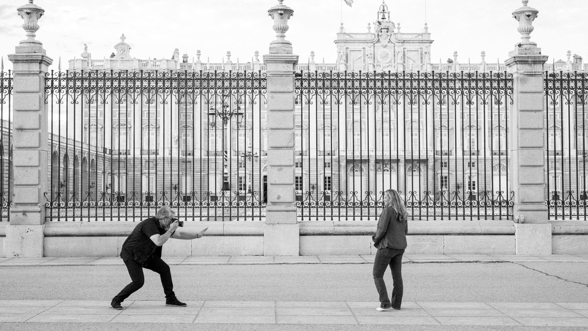 a man and woman standing in front of a fence