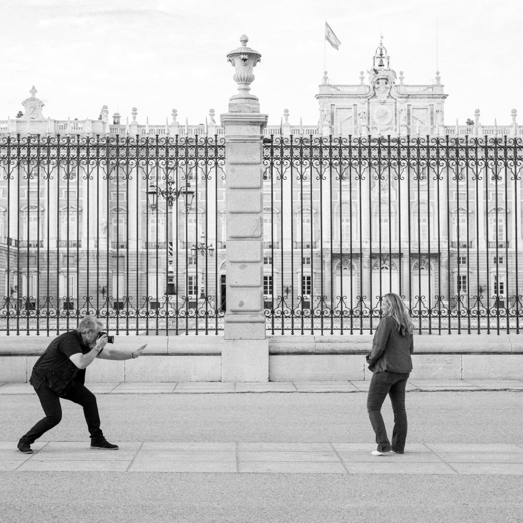 a man and woman standing in front of a fence