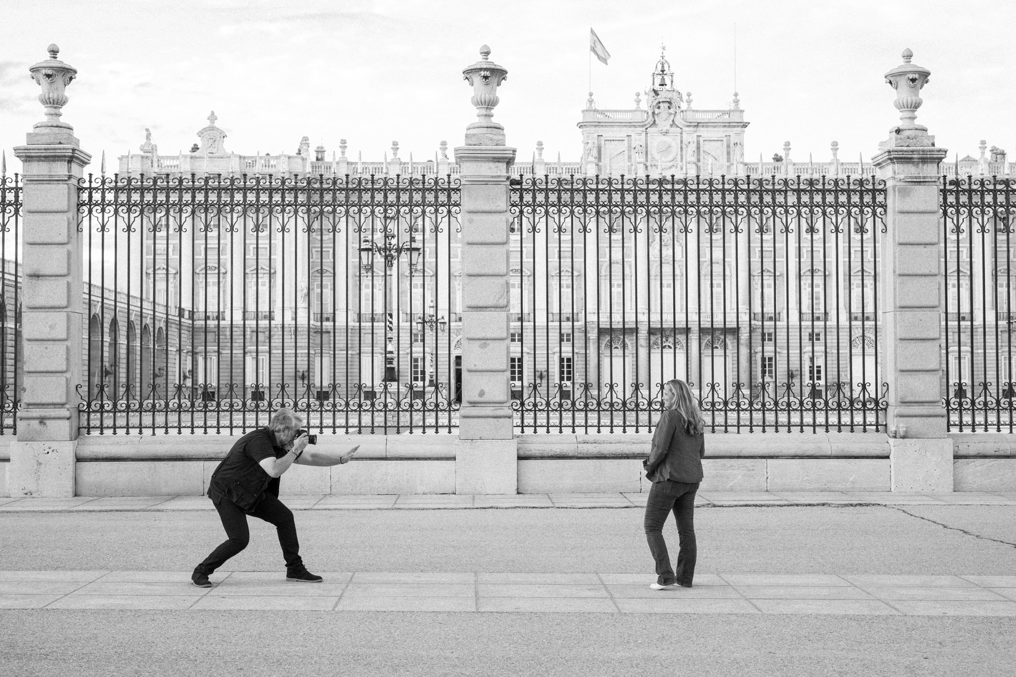 a man and woman standing in front of a fence