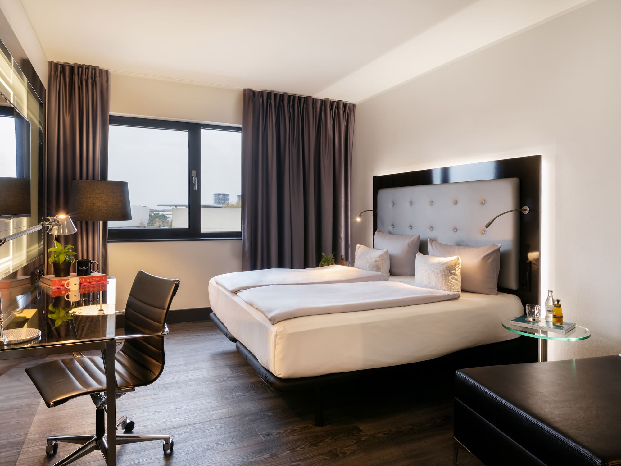 Modern hotel room with double bed, work desk, window, and TV.