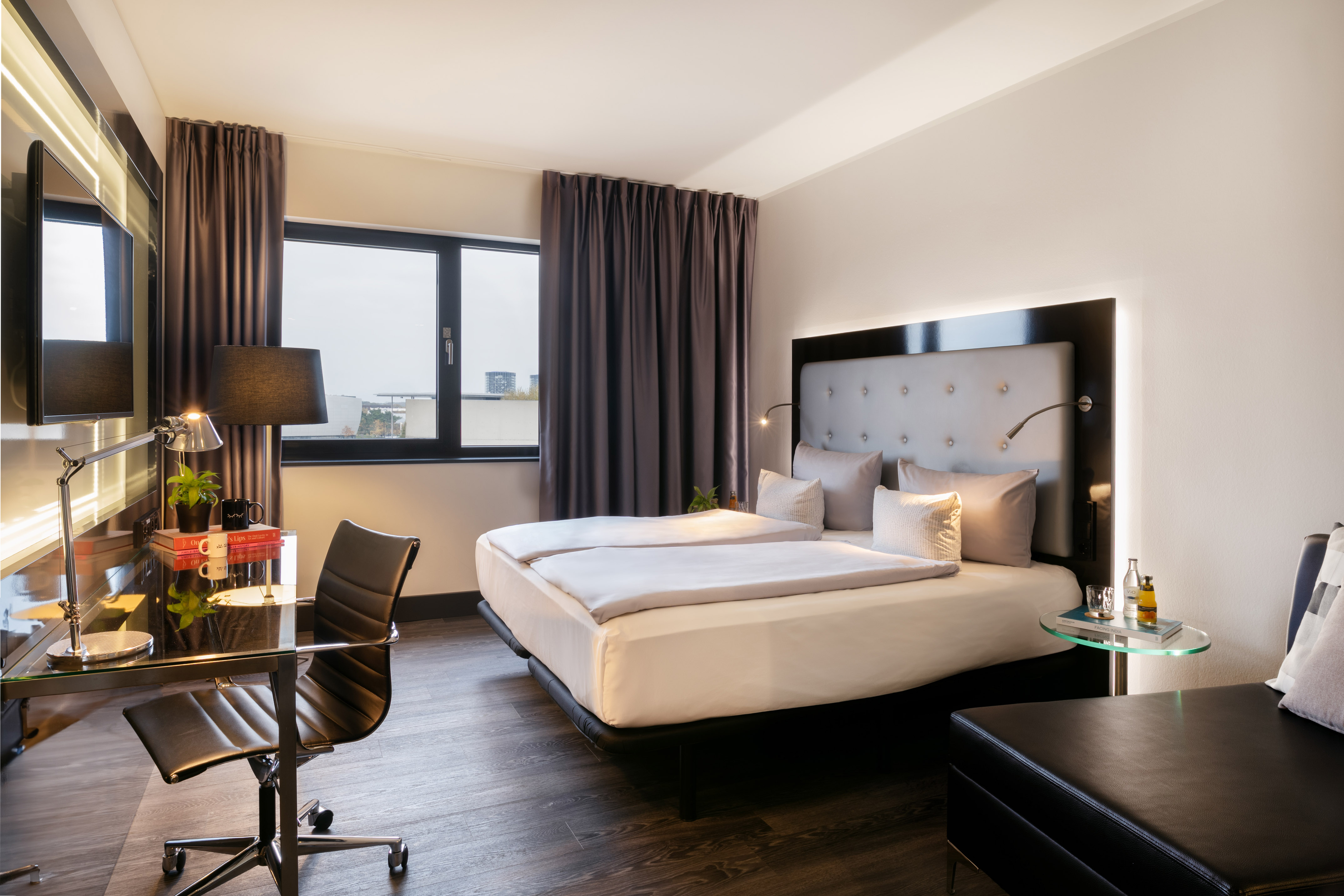 Modern hotel room with double bed, work desk, window, and TV.