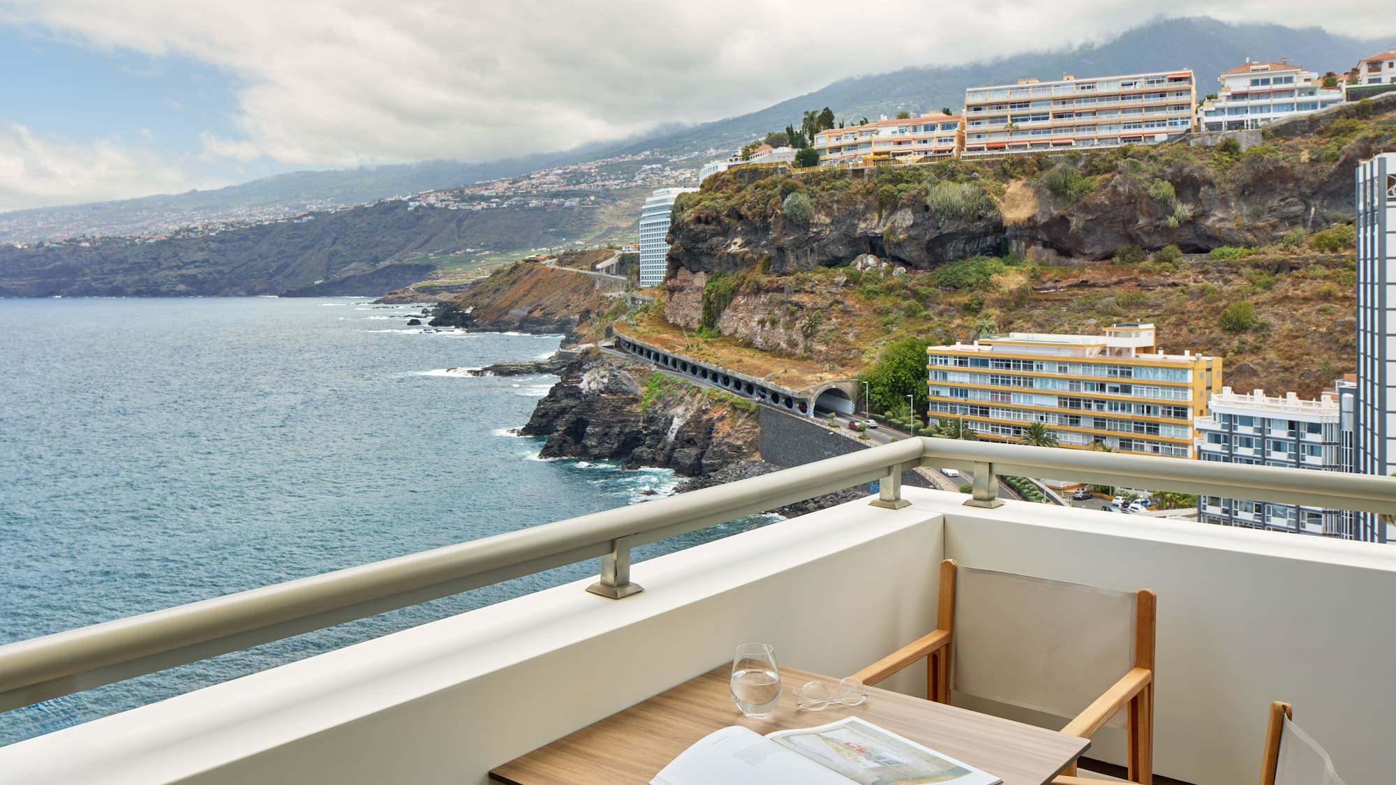 a table and chairs on a balcony overlooking a body of water