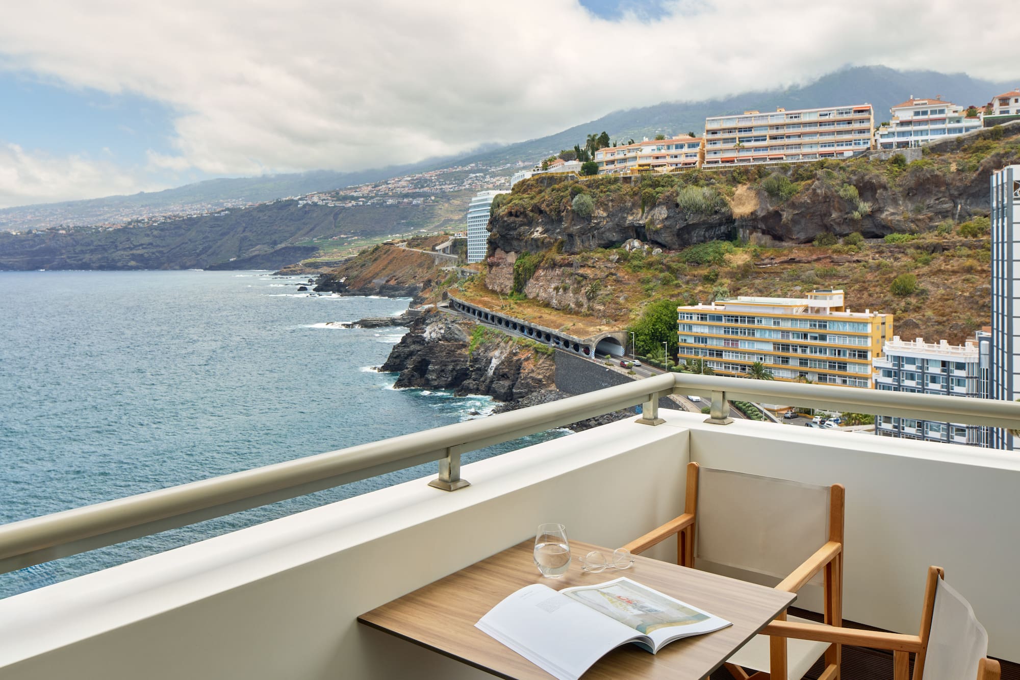 a table and chairs on a balcony overlooking a body of water