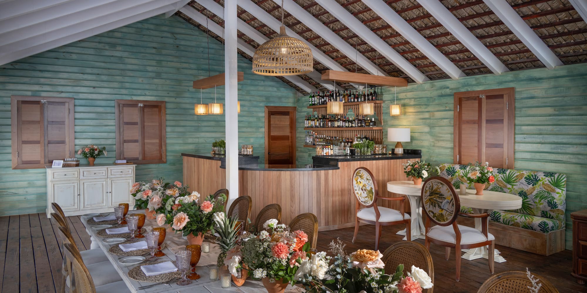 a room with a bar and tables with flowers