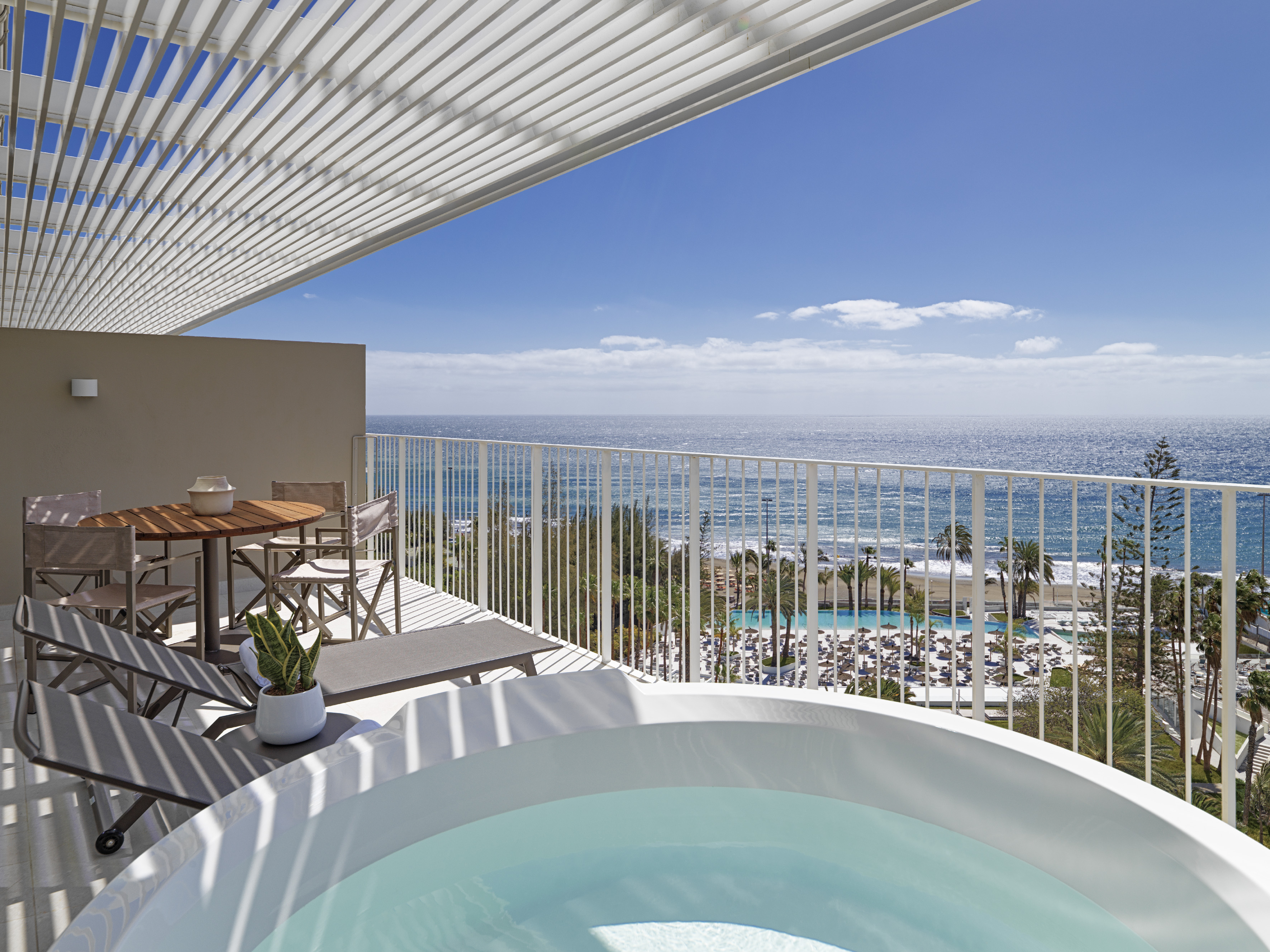 Modern balcony with hot tub, panoramic ocean view, and resort amenities.