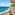 Balcony overlooking turquoise sea, sandy beach, and distant resort town.