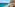 Resort balcony with blue ocean, sandy beach, and distant coastal city view.