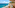 Balcony overlooking turquoise sea, sandy beach, and distant resort town.