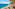 Balcony overlooking turquoise sea, sandy beach, and distant resort town.