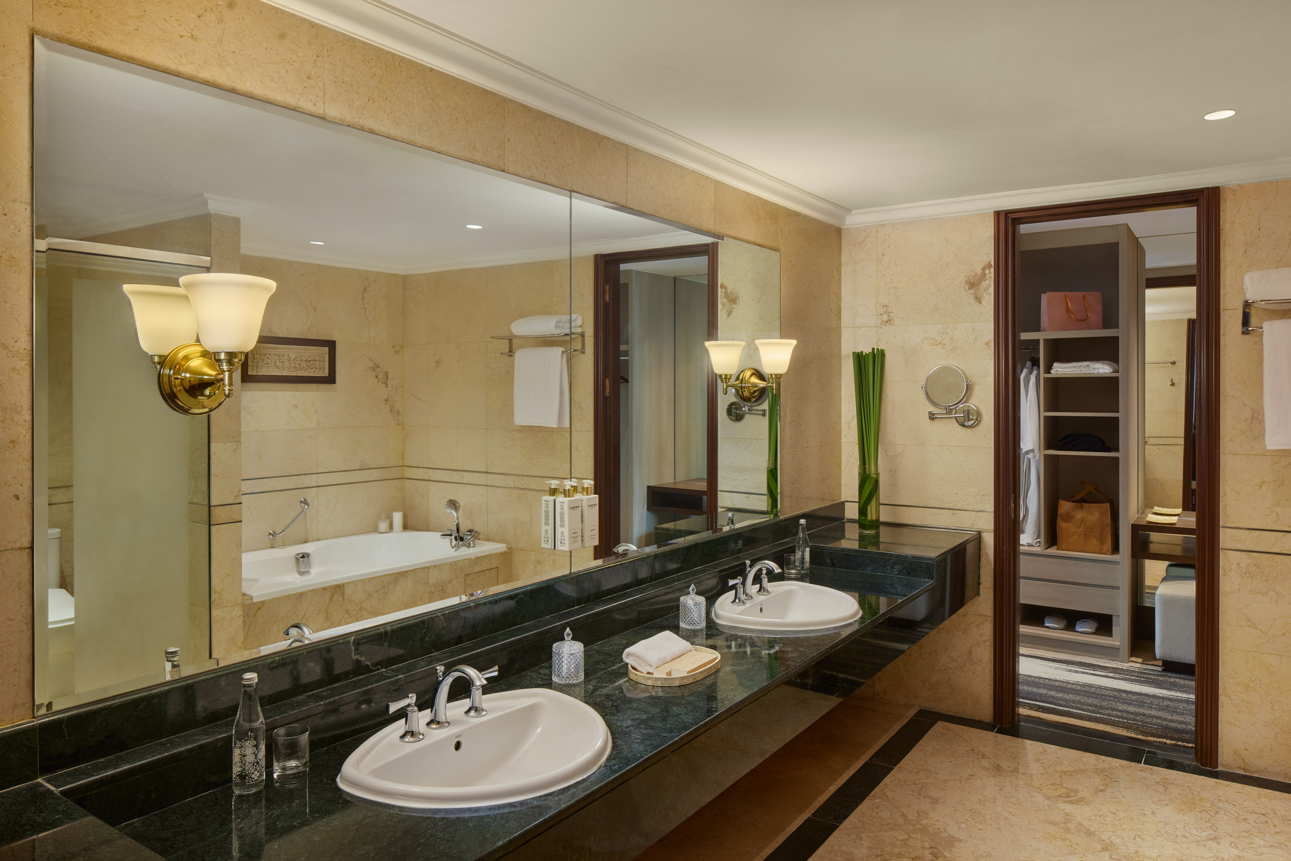 Modern hotel bathroom with double vanity, green marble countertop, and large mirror.