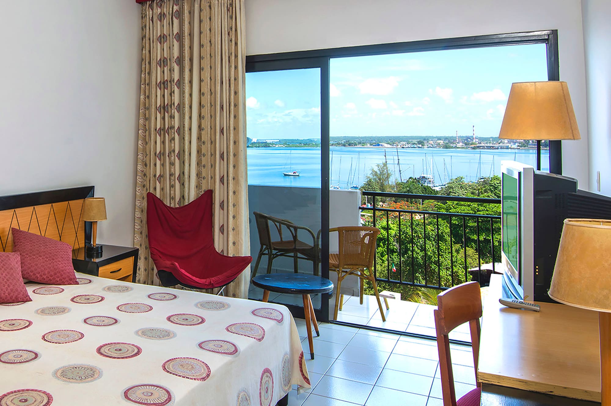 a room with a bed and a television and a balcony overlooking the water