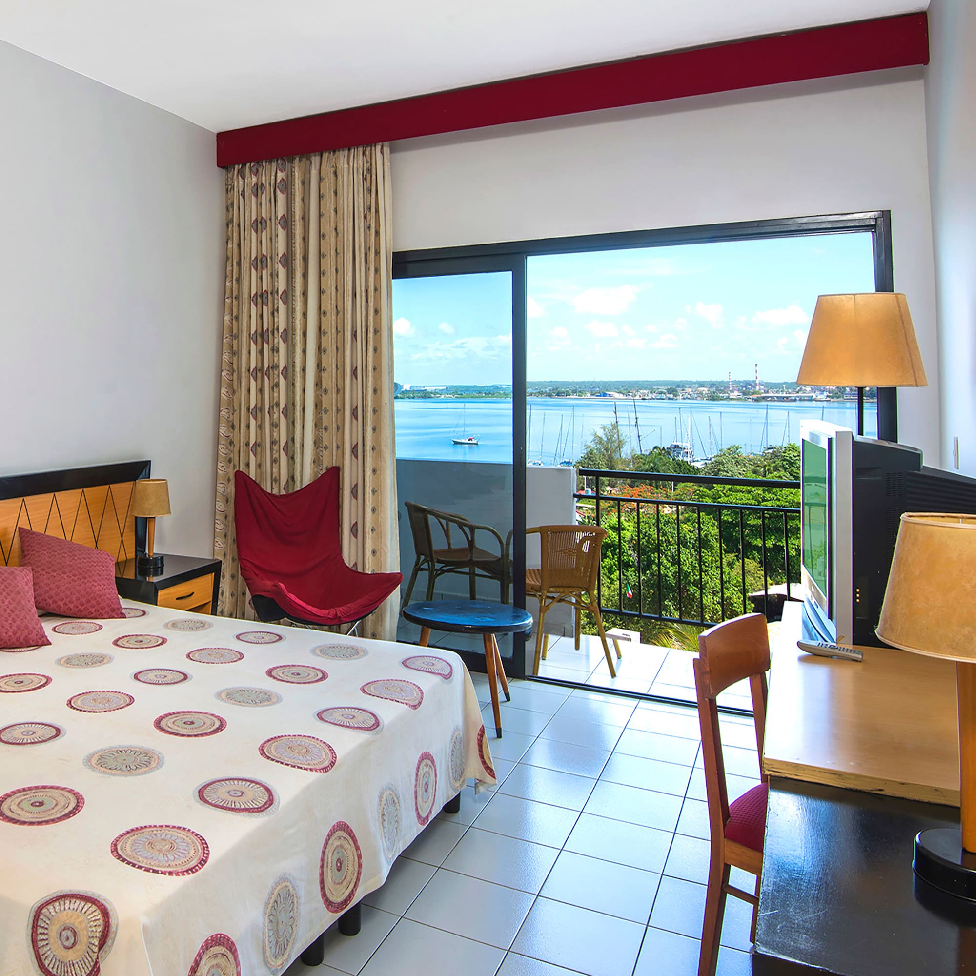 a room with a bed and a television and a balcony overlooking the water