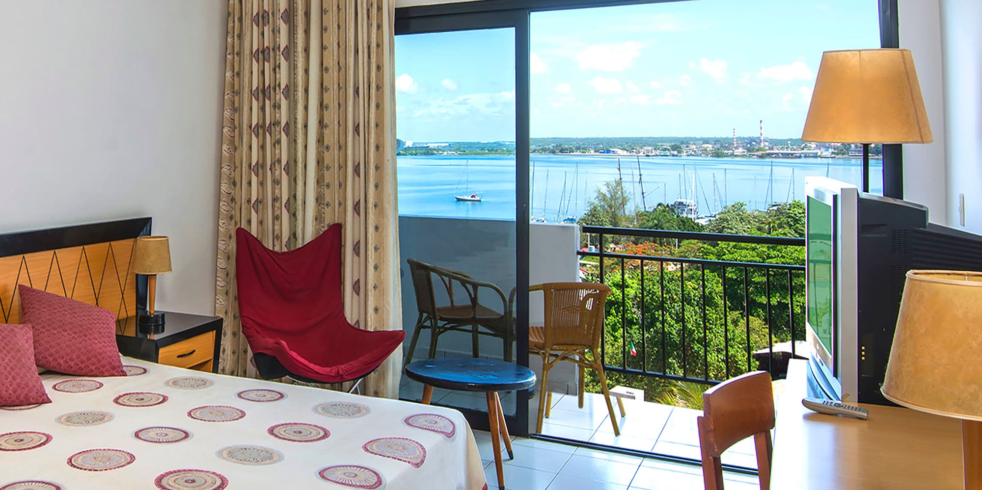 a room with a bed and a television and a balcony overlooking the water