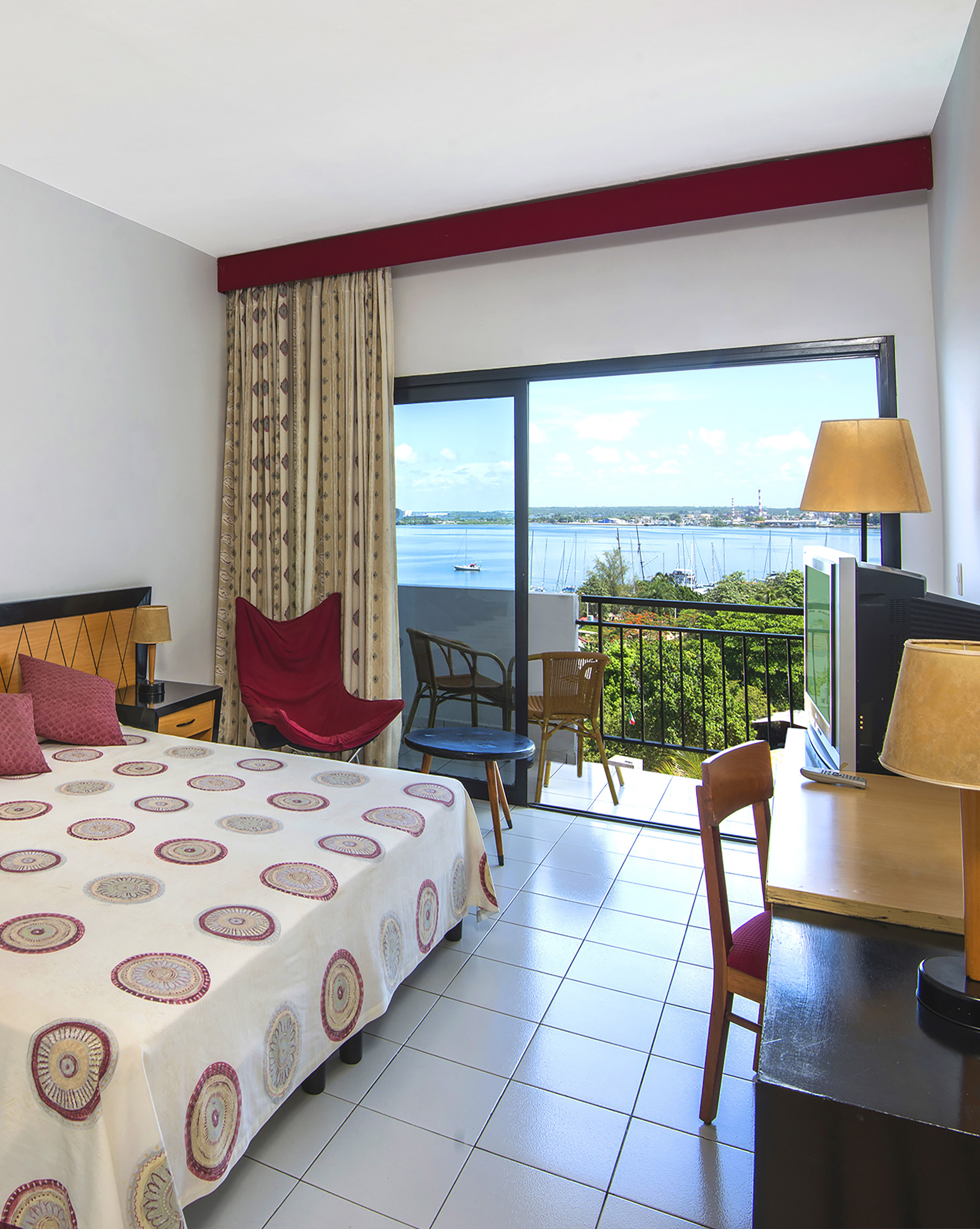 a room with a bed and a television and a balcony overlooking the water