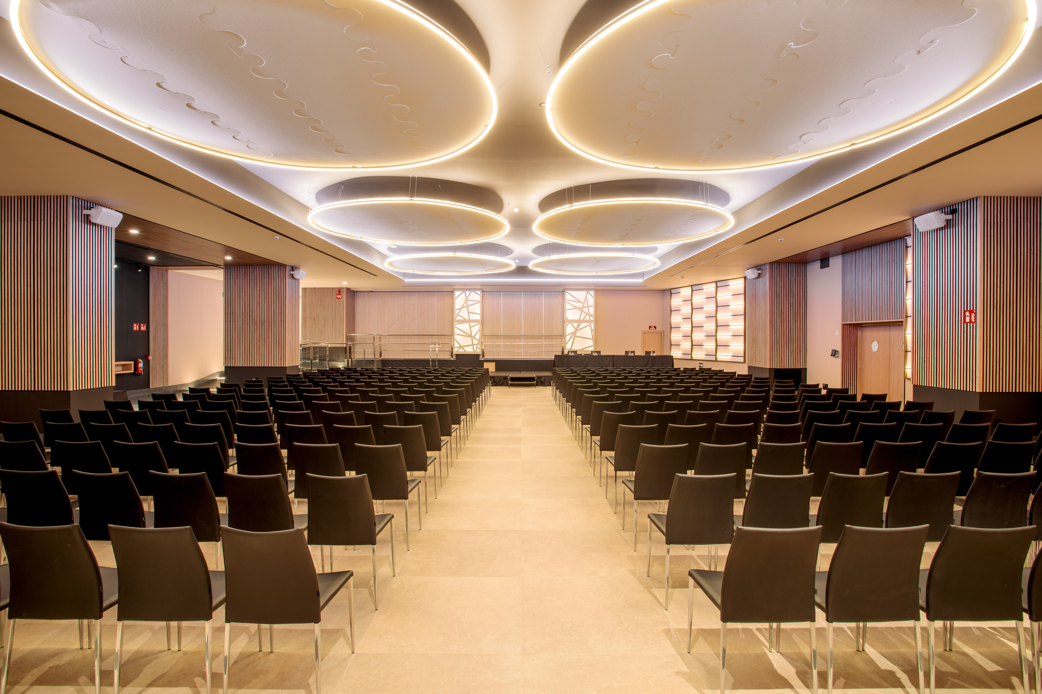 Modern conference hall interior, empty rows of chairs, illuminated stage.