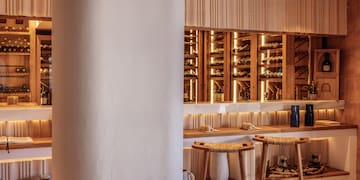 a wine cellar with stools and a shelf with wine bottles