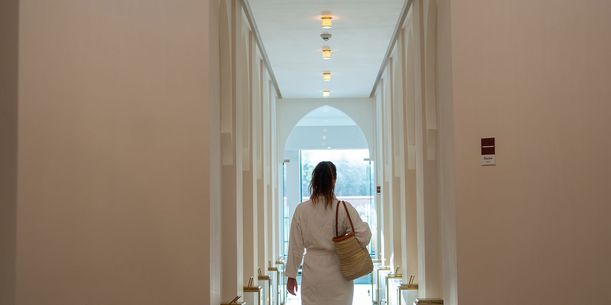 a woman in a white robe walking down a hallway