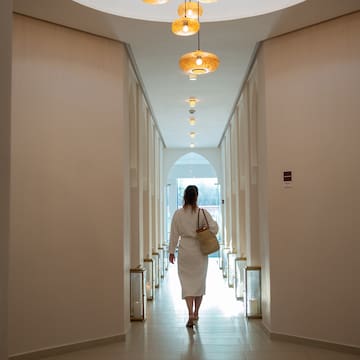 a woman in a white robe walking down a hallway