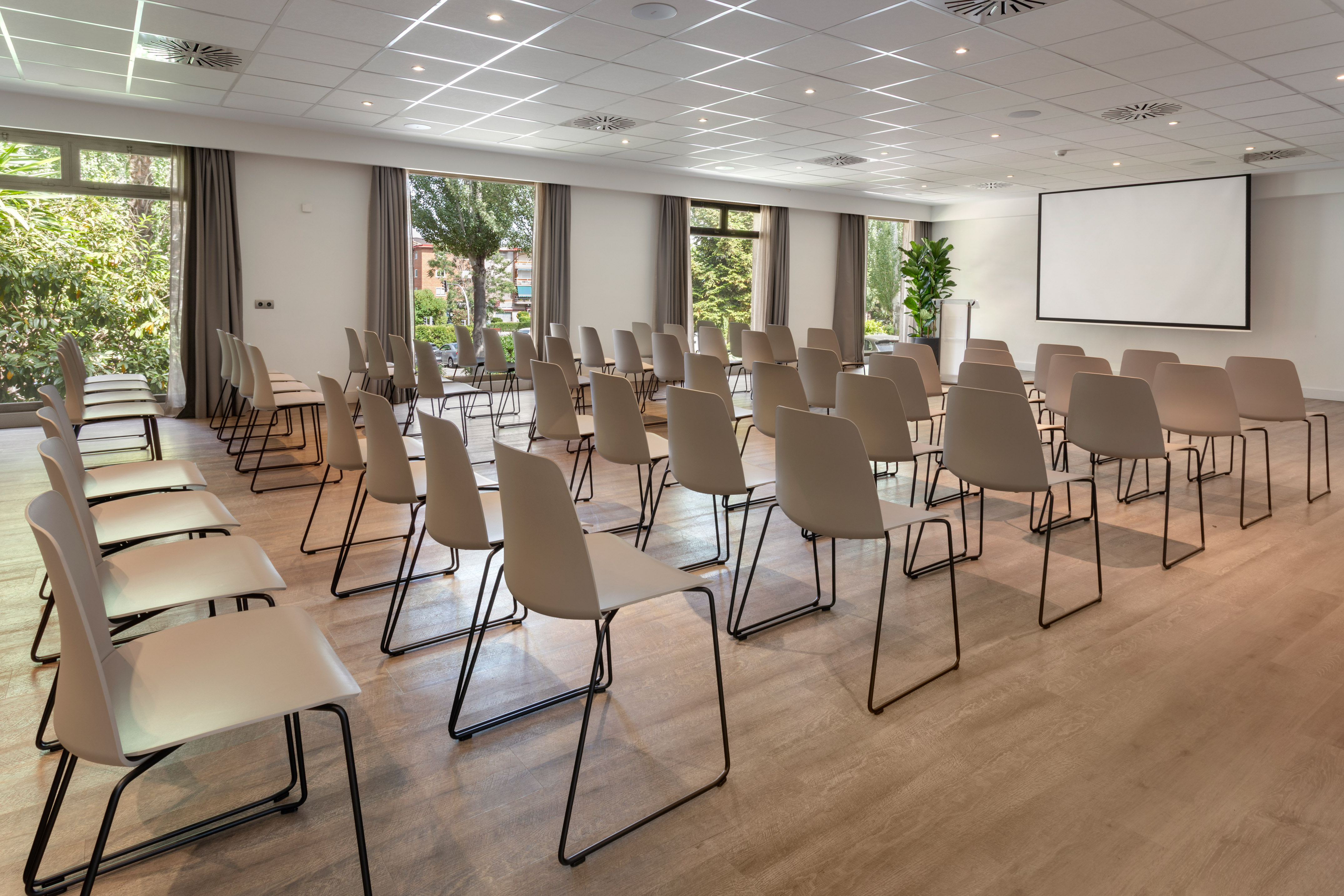 Modern conference room with screen, rows of chairs, and large windows.