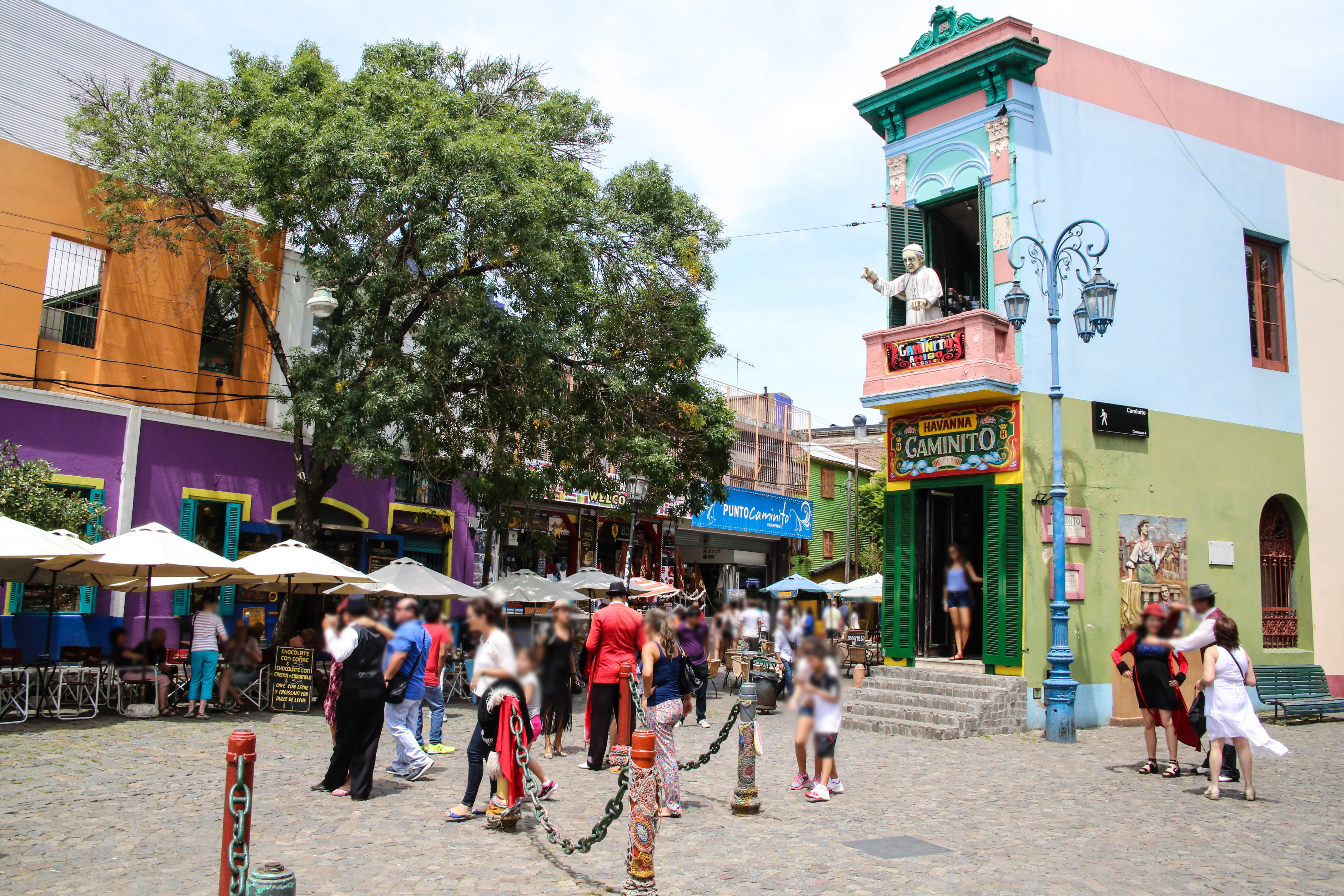 Colorful Caminito street in La Boca, Buenos Aires, with people and iconic statue.