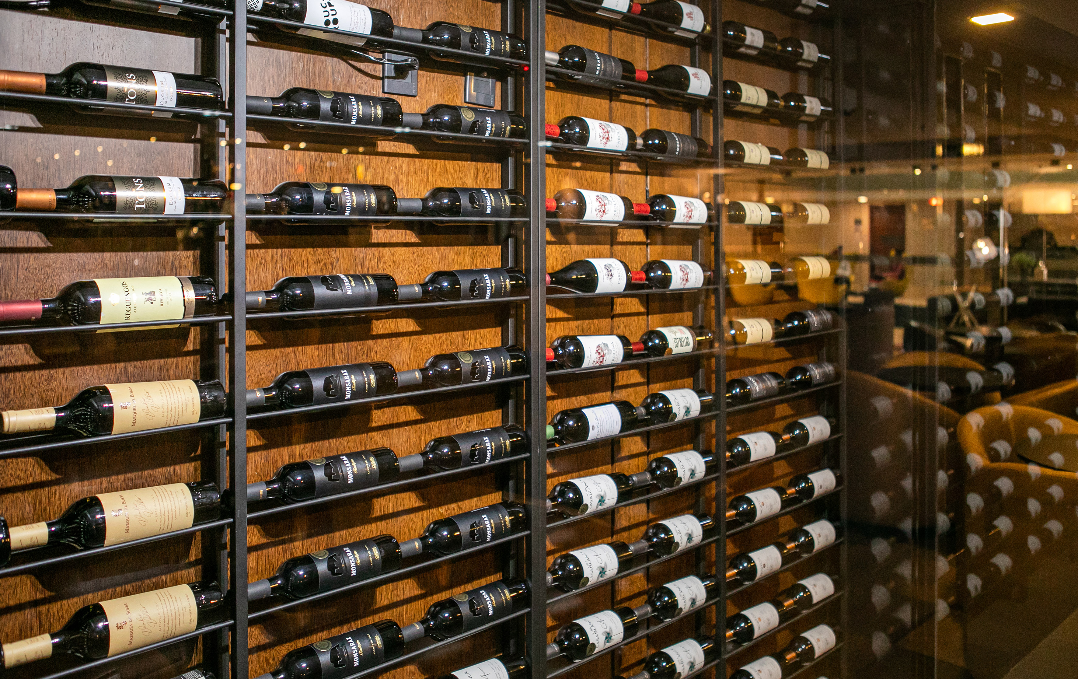 Rows of wine bottles on a modern metal rack in a restaurant wine cellar.